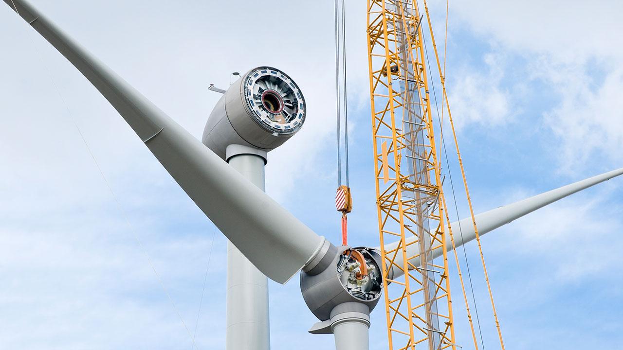 A crane lifts wind turbine blades during scheduled maintenance